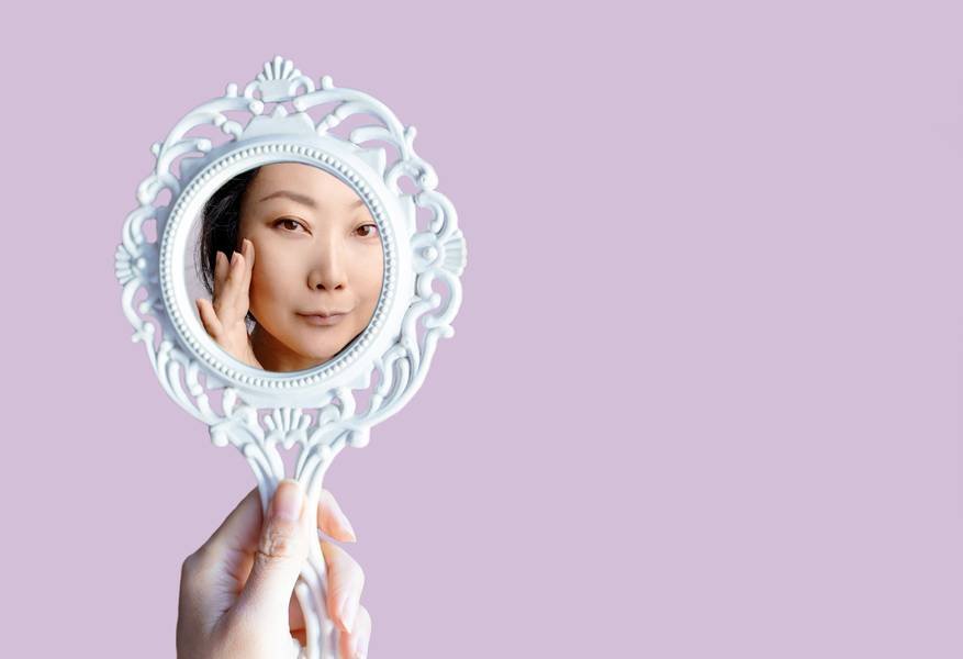 Productos de skincare estilo coreano sobre superficie blanca con flores