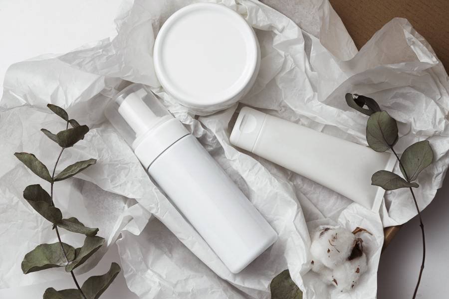 Frascos y envases cosméticos de skincare sobre superficie blanca