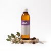 Botella ámbar de 1 litro de Aceite de Jojoba Golden Virgen de LTSH, con hojas y semillas de jojoba sobre piedra
